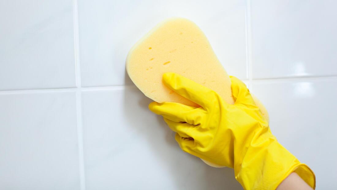 hand in yellow gloves cleaning the walls